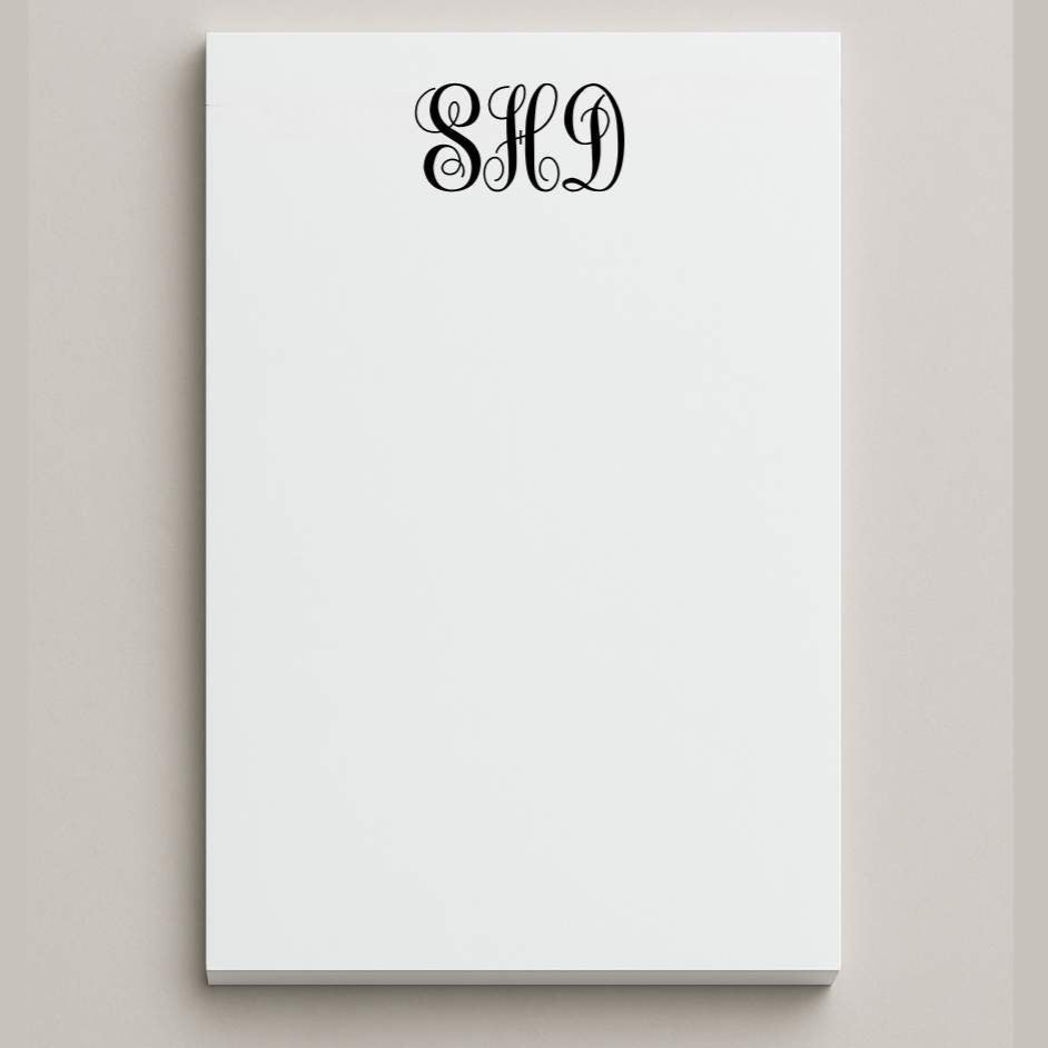 White notepad with black monogram on a light gray background
