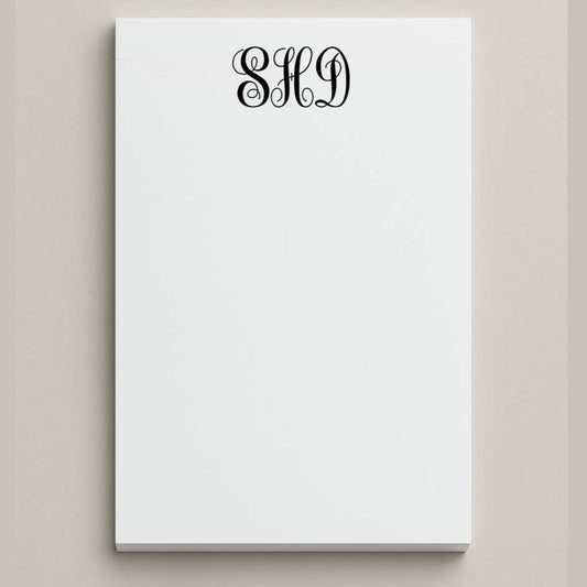 White notepad with black monogram on a light gray background